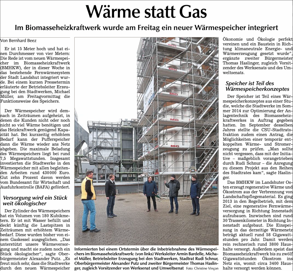Fünf Personen stehen vor dem neu integrierten Wärmespeicher des Biomasseheizkraftwerks Landshut bei der Inbetriebnahme.