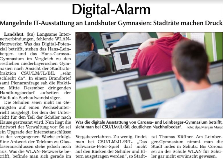 Schüler arbeiten an Laptops und Tablets im Unterricht. Im Hintergrund trägt ein Schüler ein rotes Oberteil.